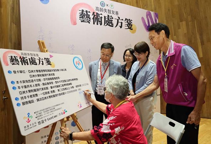 亞大校長蔡進發(後排左1)頒發「藝術處方箋」給「北柳憶站」，由失智長輩代表戴林阿嬤(前)署名。圖／亞大提供